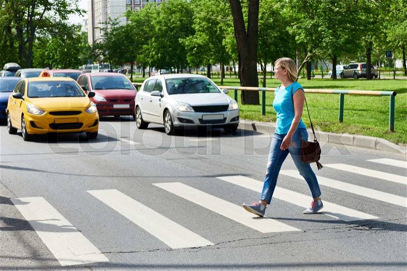 Woman crossing the street at a pedestrian crossing, stock photo