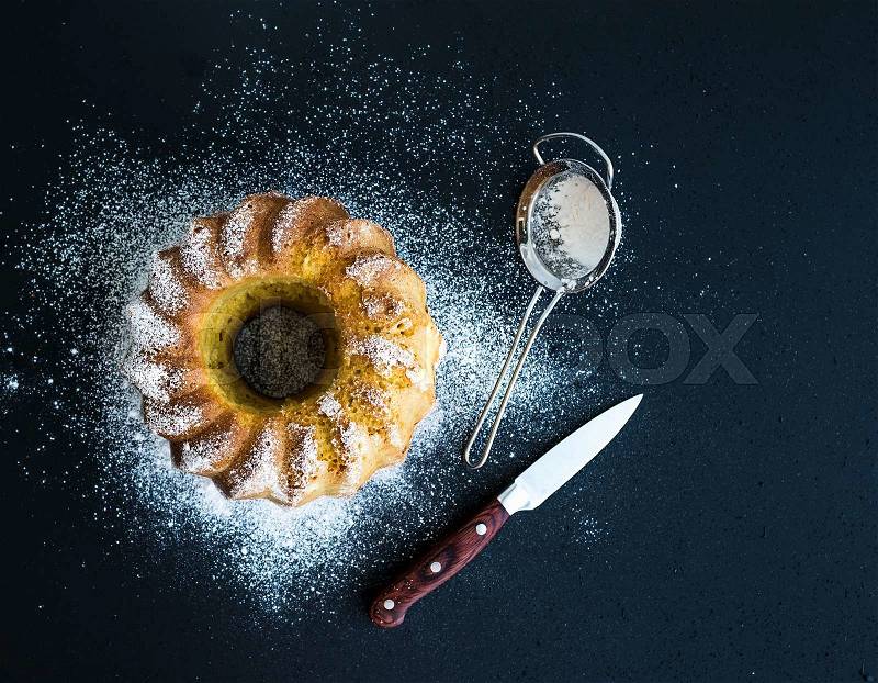 Moist orange bundt yoghurt cake with sugar powder, dark grunge background. Top view, stock photo
