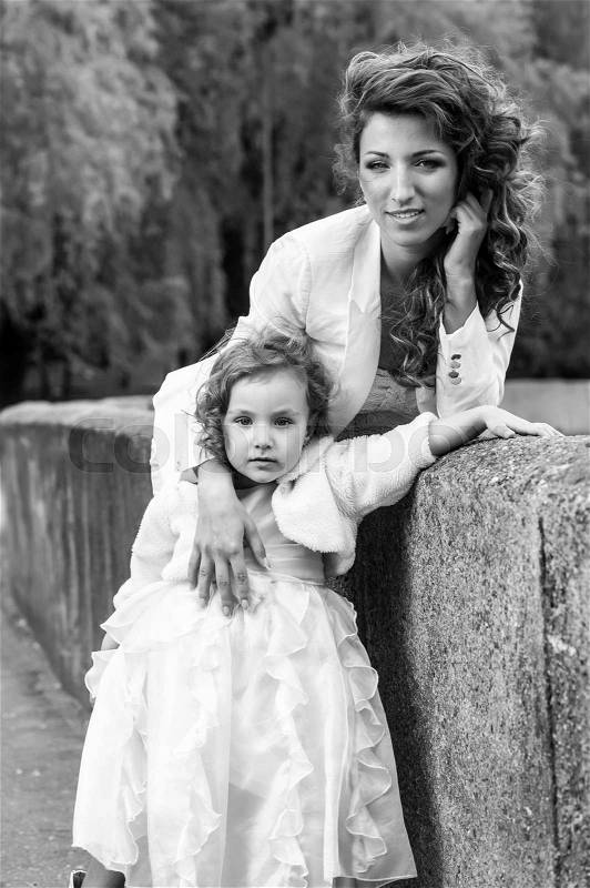 Young happy mother with little daughter pose outdoors, stock photo