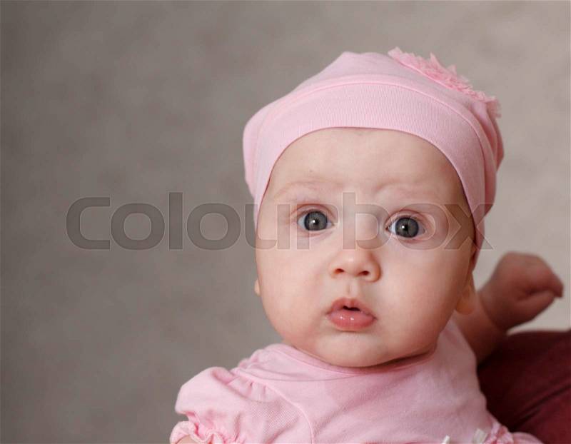 Close up portrait of beautiful little baby in pink dress and cap, stock photo