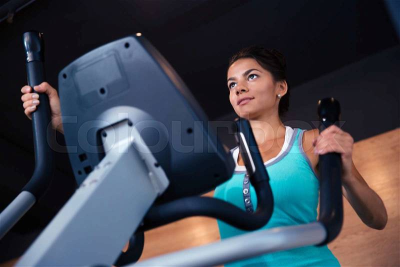 Beautiful woman workout on exercises machine in fitness gym, stock photo