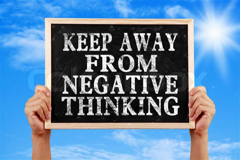 Hands holding blackboard with text Keep Away From Negative Thinking against blue sky background, stock photo