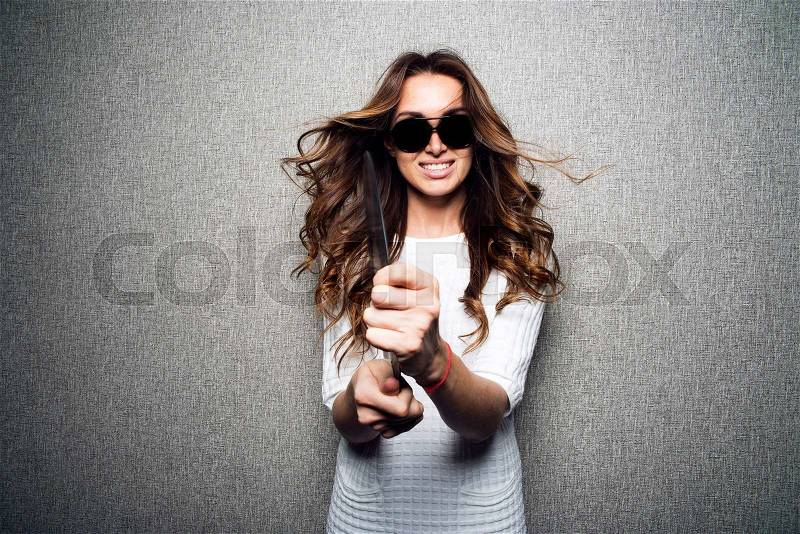 Portrait of beautiful smiling dj woman with black long curly hair in sunglasses, white dress and shoes poses on grey background holding vinyl.Windy.Studio.Fashion look.Stylish image.Charming smile.Modern clothes.Deejay, stock photo