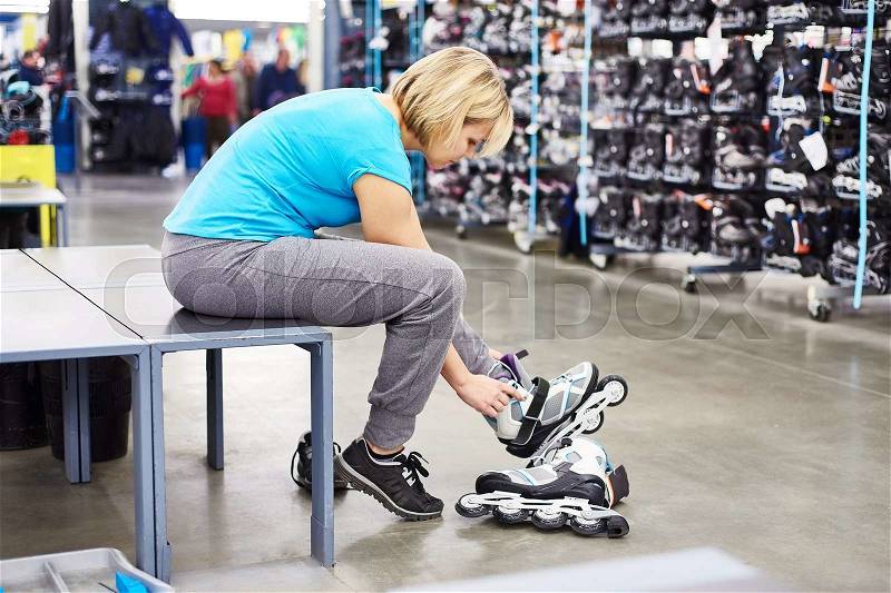 Woman wears roller skates in the sports shop, stock photo
