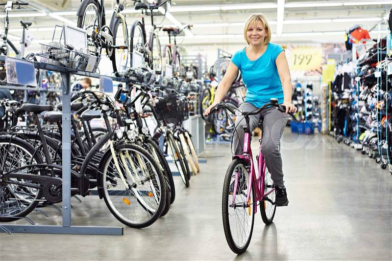 Attractive athletic woman testing the bike in the store, stock photo
