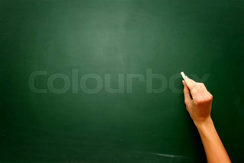 Female teen hand to draw something on blackboard with chalk , stock photo