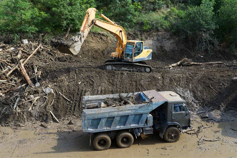 Excavator clears the road from landslide, stock photo
