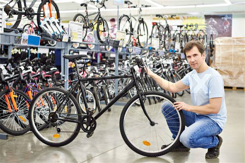 Man checks a bike before buying in the sports shop, stock photo