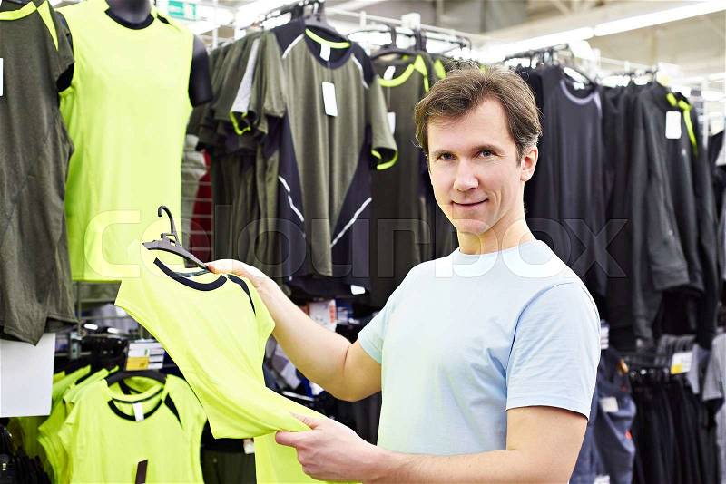 Happy man shopping for sport t-shirt in shop, stock photo