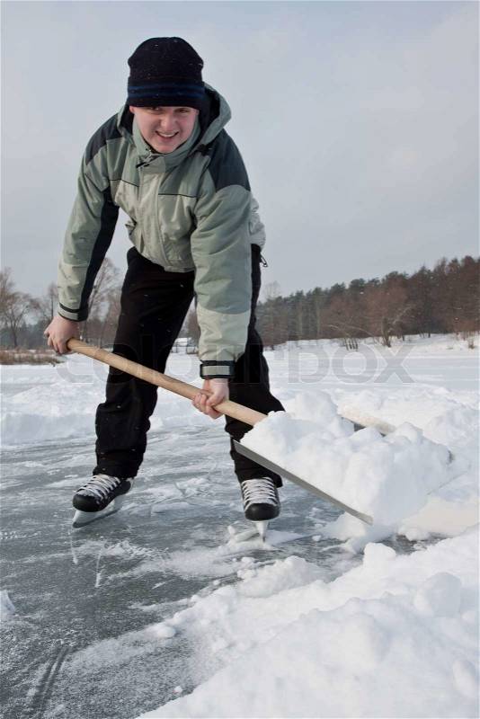 Man wearing skates working with snow shovel, stock photo
