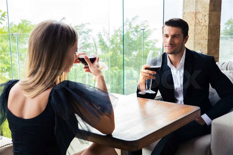 Woman and confident man drinking red wine in restaurant, stock photo