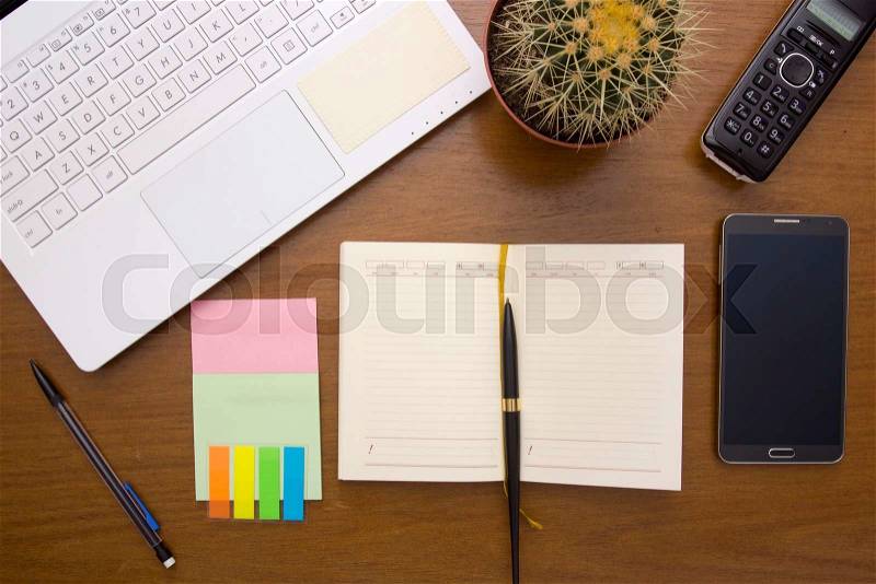 Office desk with office items - diary and laptop, cactus and phones, stock photo