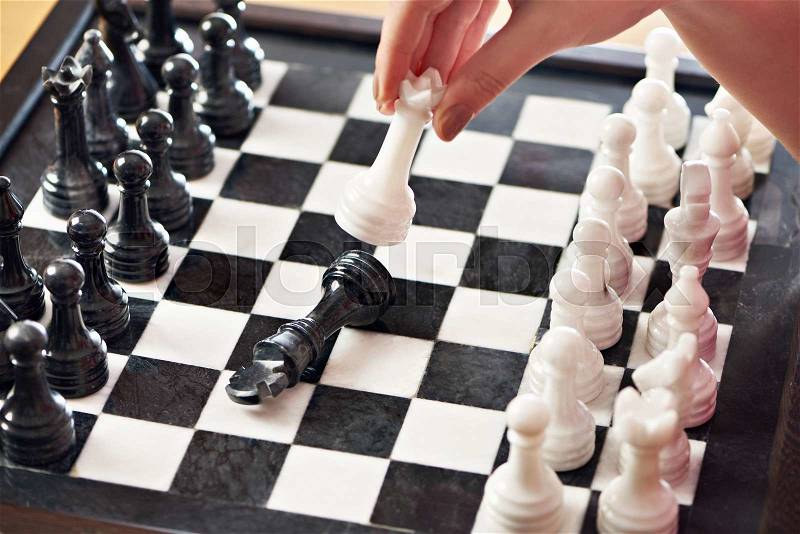 Hand with white queen hits black king closeup, stock photo