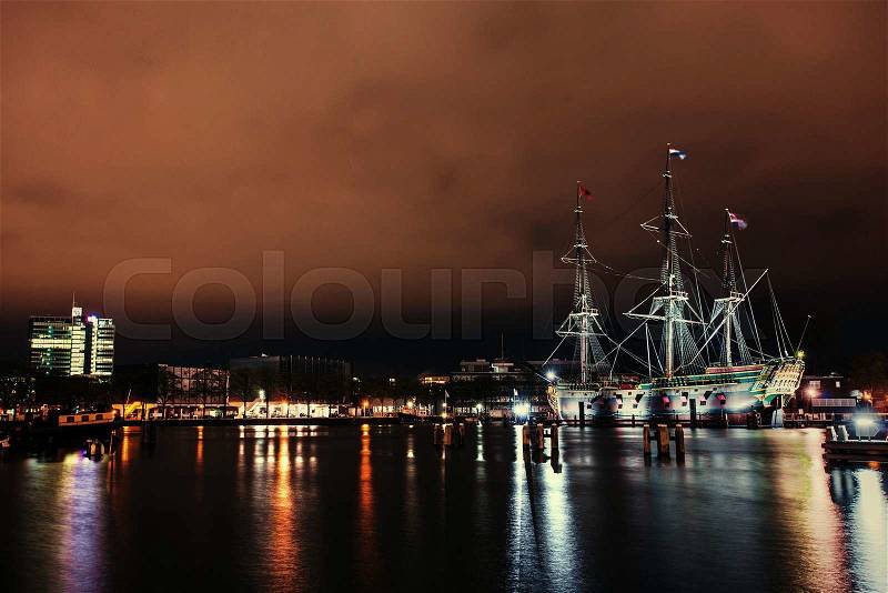 Beautiful night in Amsterdam. Night illumination of buildings and boats near the water in the canal. , stock photo