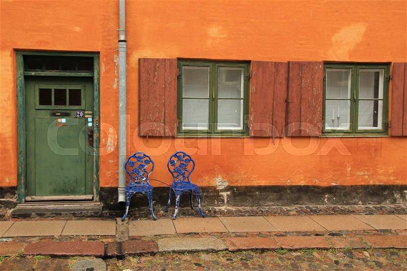 Two striking blue chairs on the square with the famous painted terraced houses in the capital Copenhagen in Denmark in the wet summer, stock photo