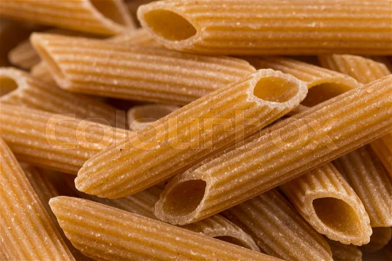 Wholemeal Pasta Penne as close-up shot for background, stock photo
