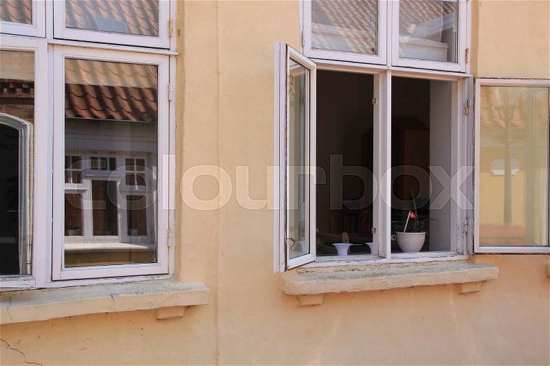 An open window because of the heat in the residential area in the village Ribe in Denmark in the summer, stock photo