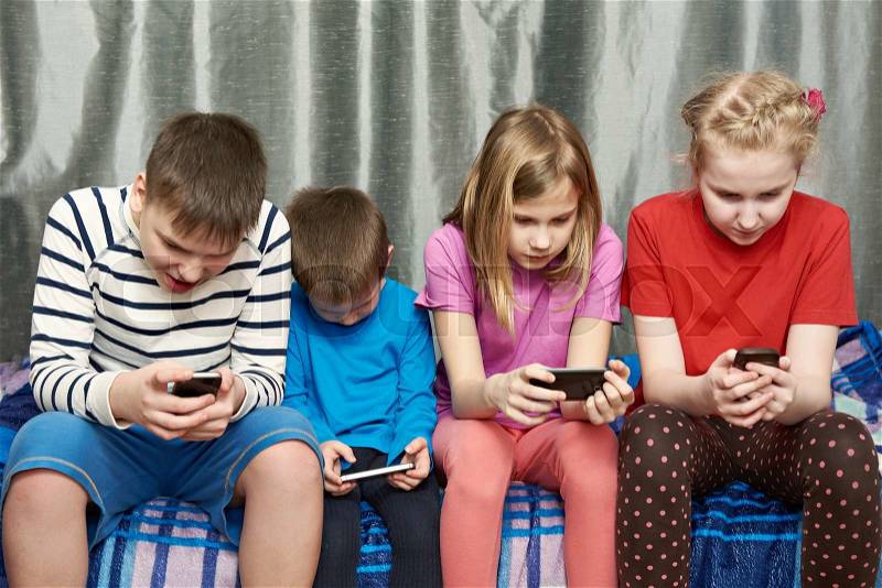 Children playing game on mobile phones at home, stock photo