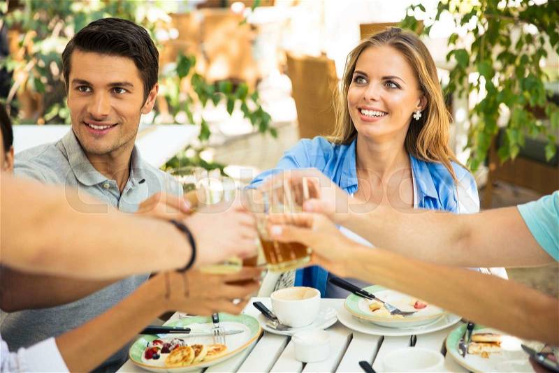 Group of a friends making toast around table at dinner party in outdoor restaurant, stock photo