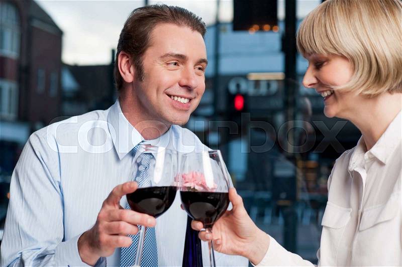 Middle aged couple toasting red wine at an outdoor cafe, stock photo