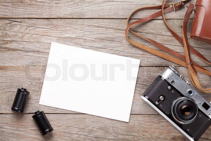 Vintage film camera and blank photo frame on wooden table. Top view, stock photo