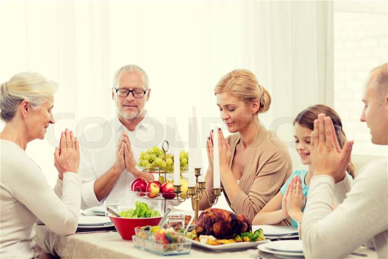 Family, holidays, generation and people concept - smiling family having dinner and praying at home, stock photo