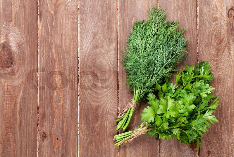 Fresh garden dill and parsley herbs on wooden table. Top view with copy space, stock photo