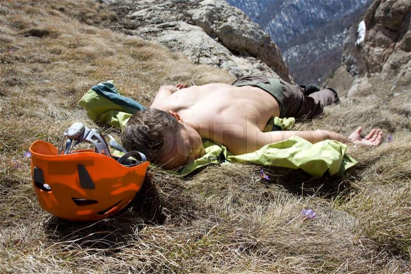 Tired hiker relaxing on the meadow, with orange helmet, stock photo