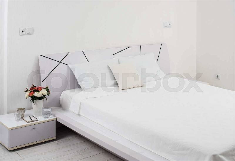 Interior of white bedroom, new linens on the bed in the hotel room, stock photo