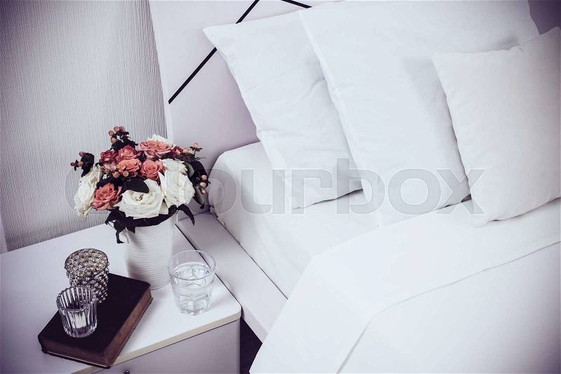 Interior of white bedroom, new linens on the bed, the room at the hotel. Bedside table decor and pillows closeup, stock photo