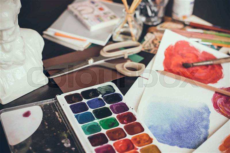 Mess in the the artist\'s studio, watercolor paints, brushes and sketches, palette and painting tools. Designer\'s working place, hipster style, stock photo