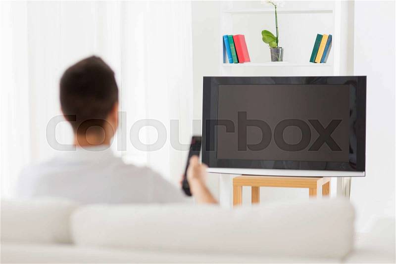 Leisure, technology, mass media and people concept - man watching tv and changing channels at home from back, stock photo