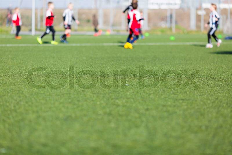 Blur of young kids playing a soccer training match outdoors on an artificial soccer pitch, stock photo