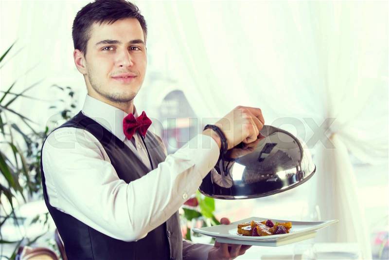 Waiter with a tray of food in the restaurant hall, stock photo