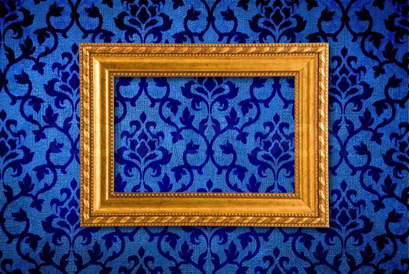 Gold frame on a vintage blue wall background, stock photo