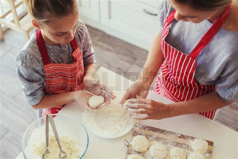 Mom with her 9 years old daughter are cooking in the kitchen to Mothers day, lifestyle photo series in bright home interior, stock photo