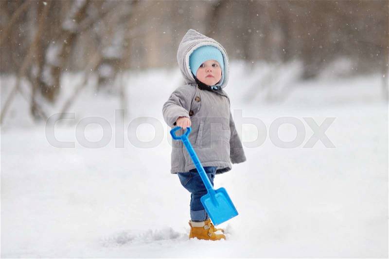 Winter portrait of beautiful toddler boy playing with snow, stock photo