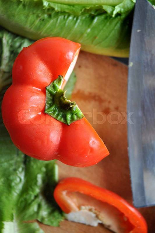 Cutting red bell pepper on wooden cutting board on top view, stock photo