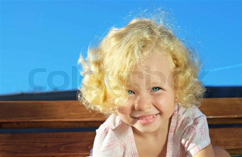 Outdoor shoot of little funny blonde curly girl, stock photo
