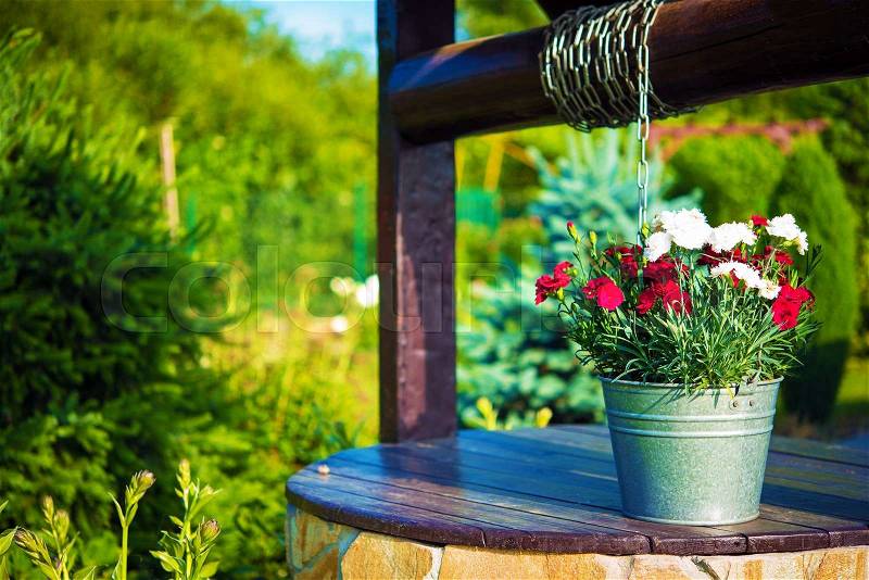 Decorative Flowers Bucket on a Well. Creative Backyard Garden Elements, stock photo