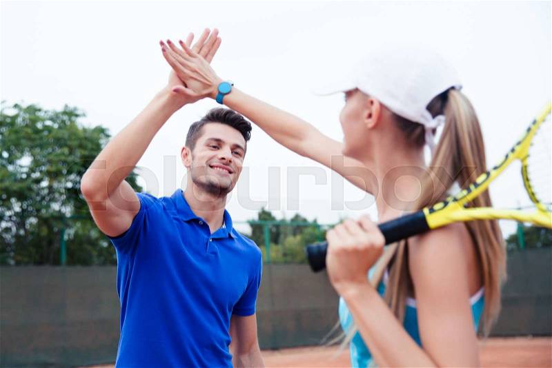 Male and female tennis players gives five at the tennis court after a match, stock photo