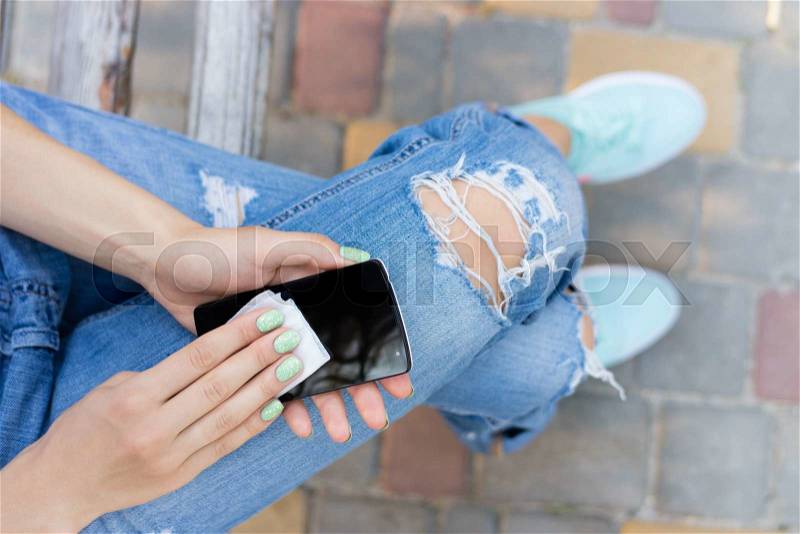 Female hands wipe the touch screen phone antibacterial wipes. Remove dust and dirt from the phone while walking, stock photo
