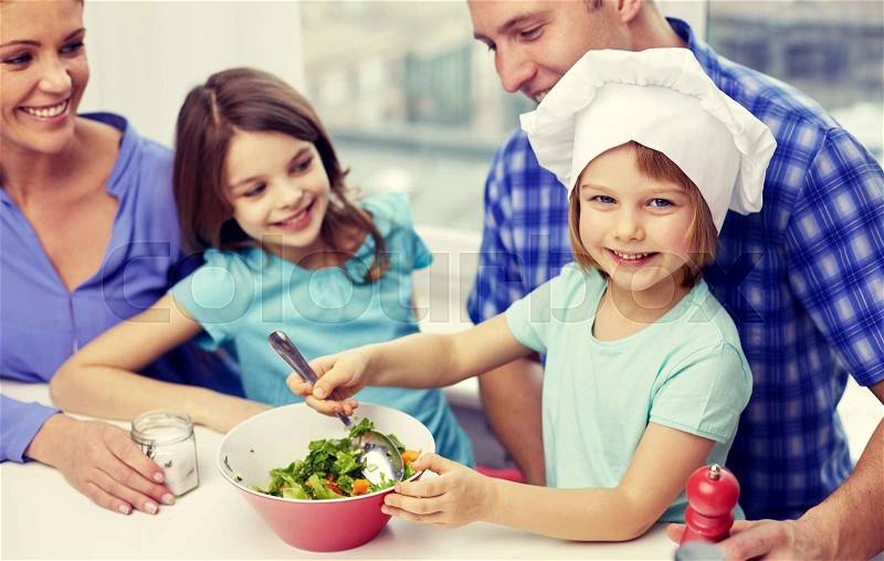 Food, children, culinary and people concept - happy family with two kids cooking vegetables at home, stock photo