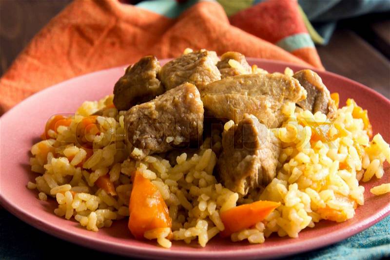 Rice pilaf with lamb meat and vegetables on wooden table and napkin close up, stock photo