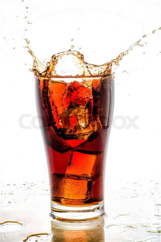 Ice cube droped in cola glass and cola splashing, stock photo