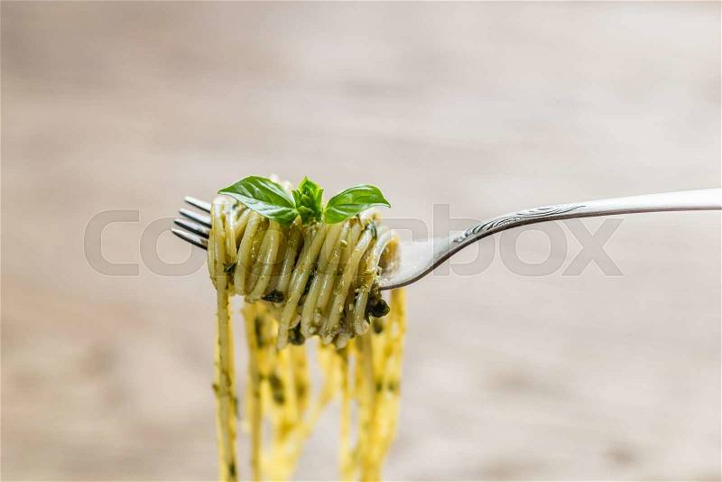 Spaghetti with pesto sauce and basil leaf on the fork, stock photo