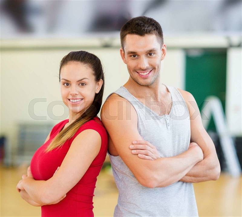Fitness, sport, training, gym and lifestyle concept - two smiling people in the gym, stock photo