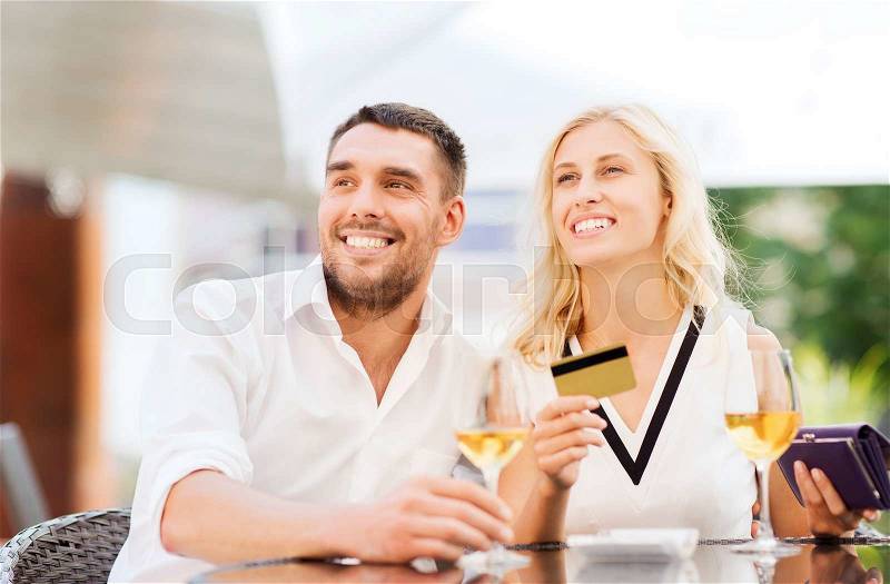Date, people, payment and relations concept - happy couple with credit card, bill and wine glasses at restaurant terrace, stock photo