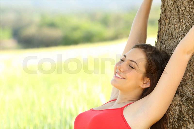 Happy woman sleeping and resting comfortable in the country under a tree shadow, stock photo