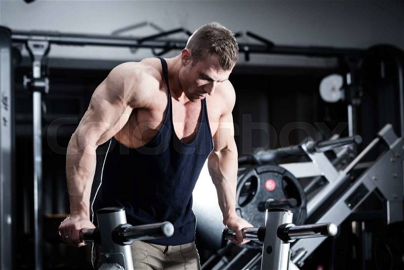 Bodybuilder man in gym doing dips as arm training , stock photo